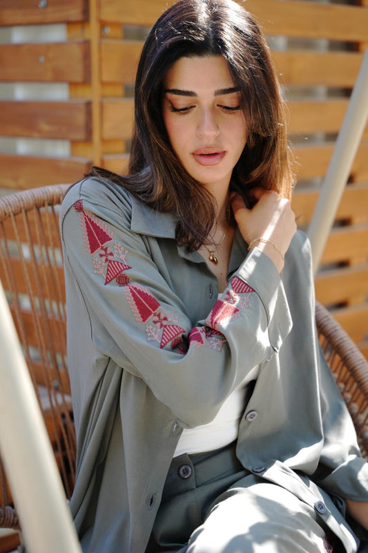Woman wearing a light gray shirt with pink tareez embroidery coord set casual yet chic sitting outdoors.